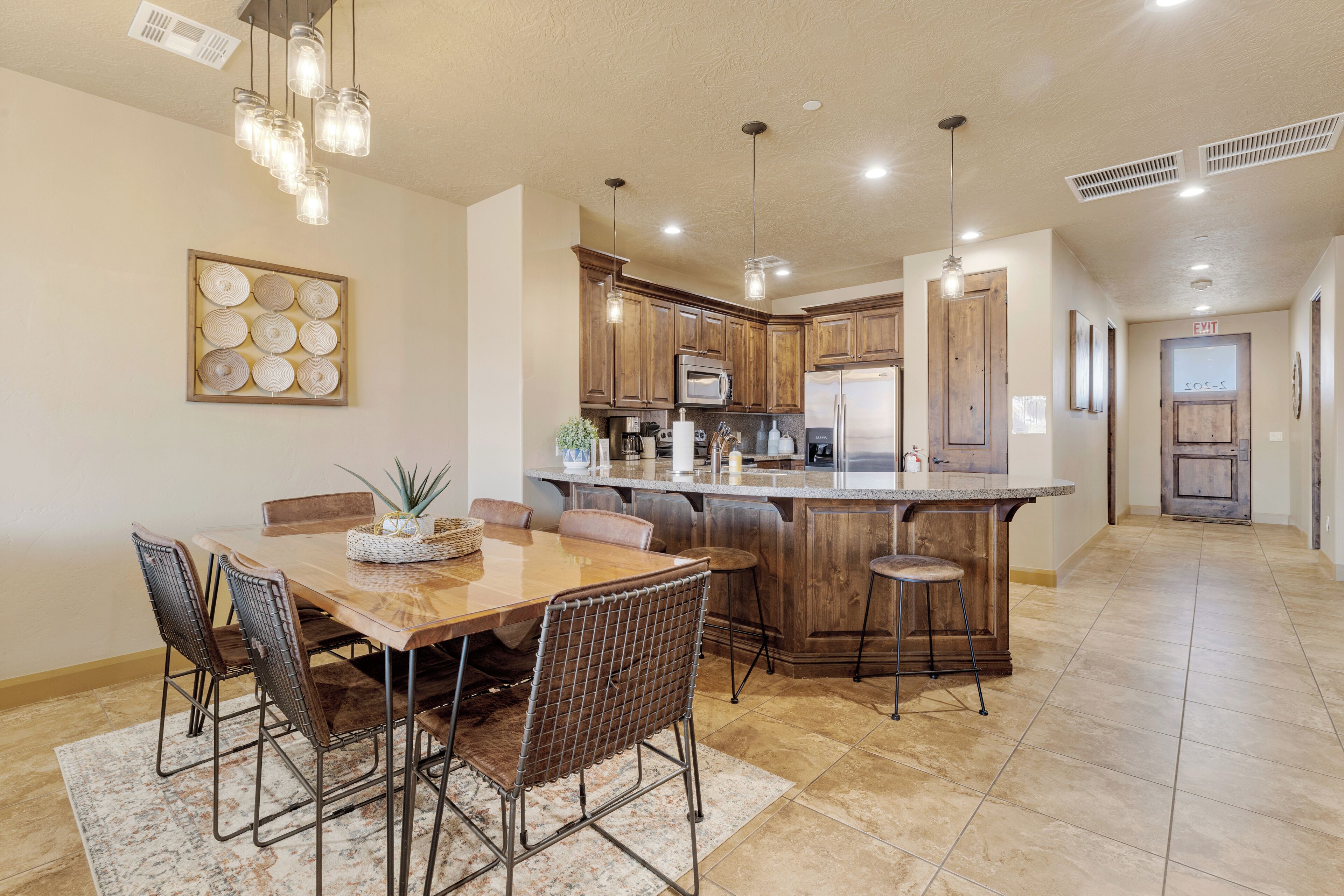 A spacious kitchen with wooden cabinets, a central island, and pendant lighting.