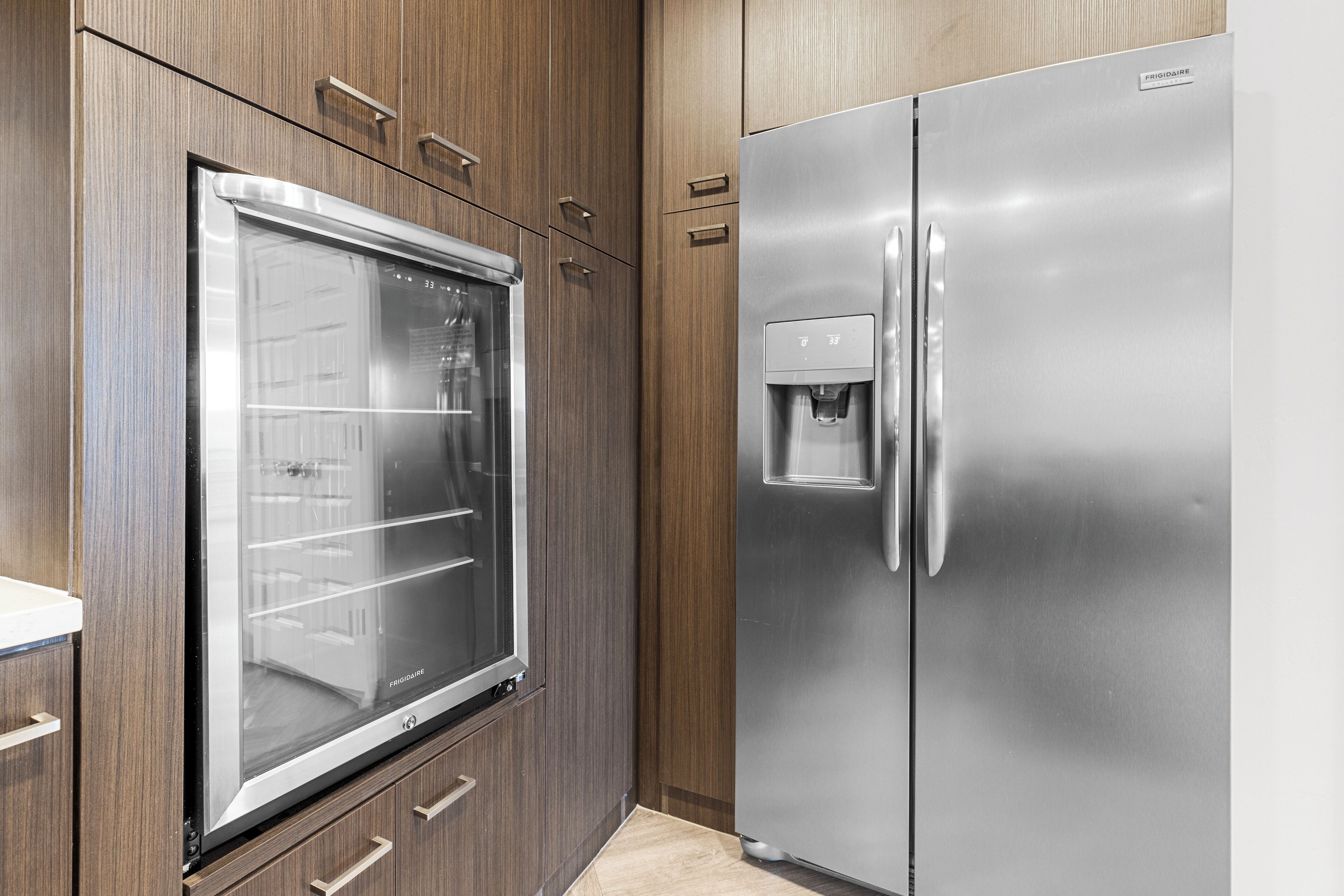 A kitchen with a stainless steel refrigerator, a built-in oven, and wooden cabinetry.