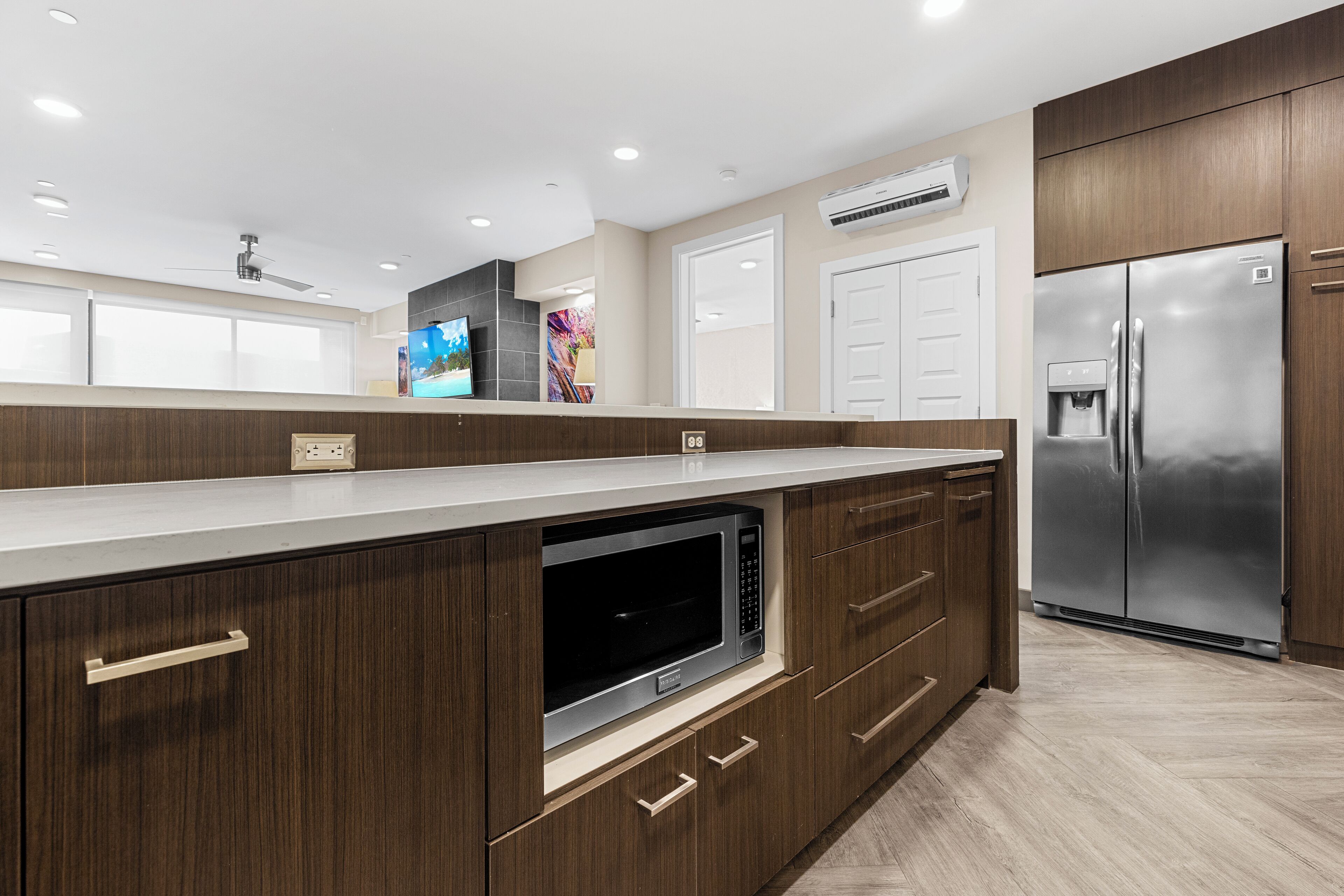A modern kitchen with wooden cabinets, a stainless steel refrigerator, and a built-in microwave.