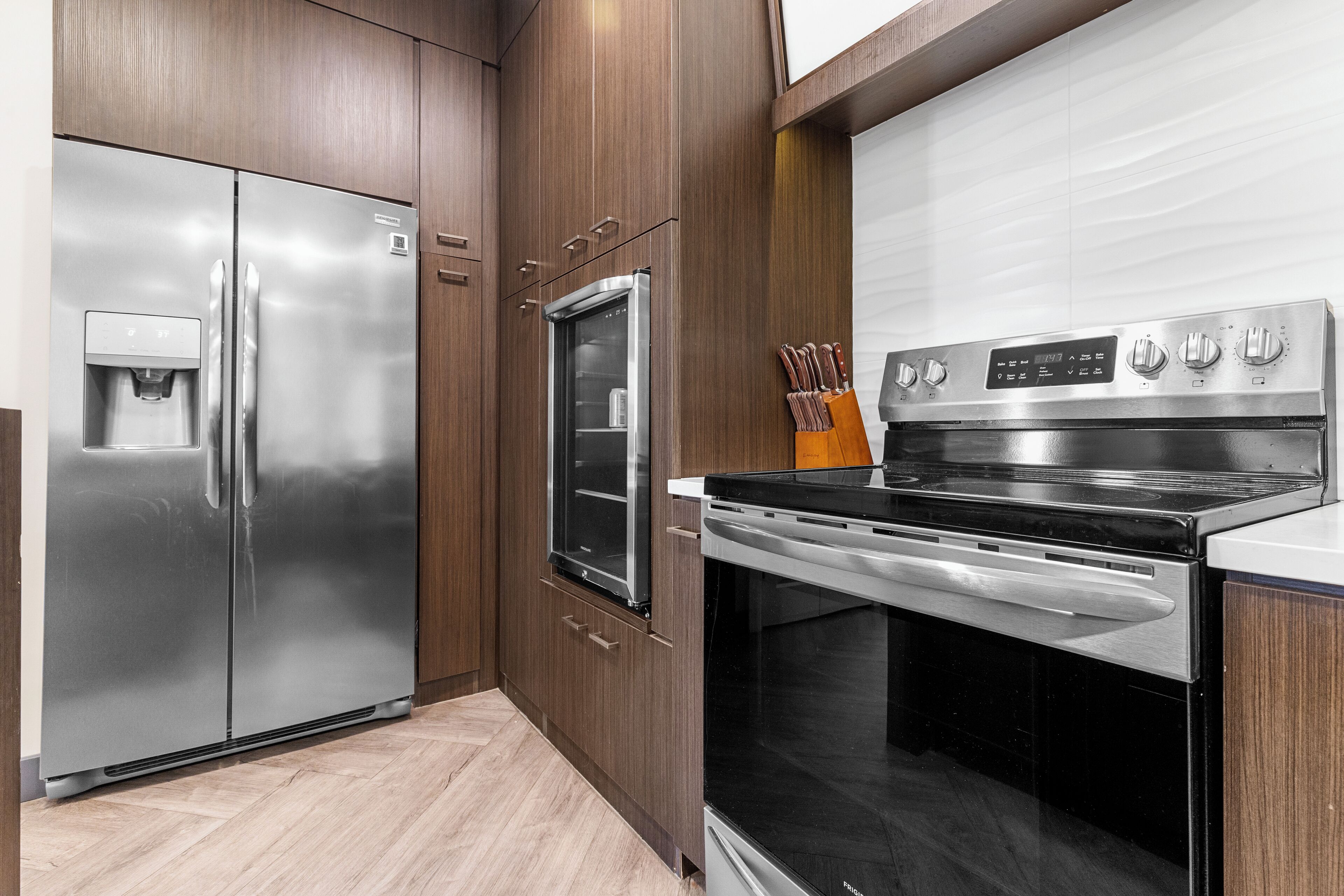 A kitchen with a stainless steel refrigerator, oven, and built-in microwave.