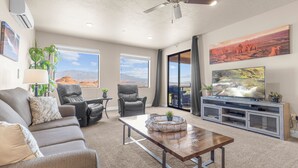 A spacious living room with a sofa, chairs, a coffee table, and a TV on a stand. - Vacation Rentals at Sand Hollow Resort (Hurricane)