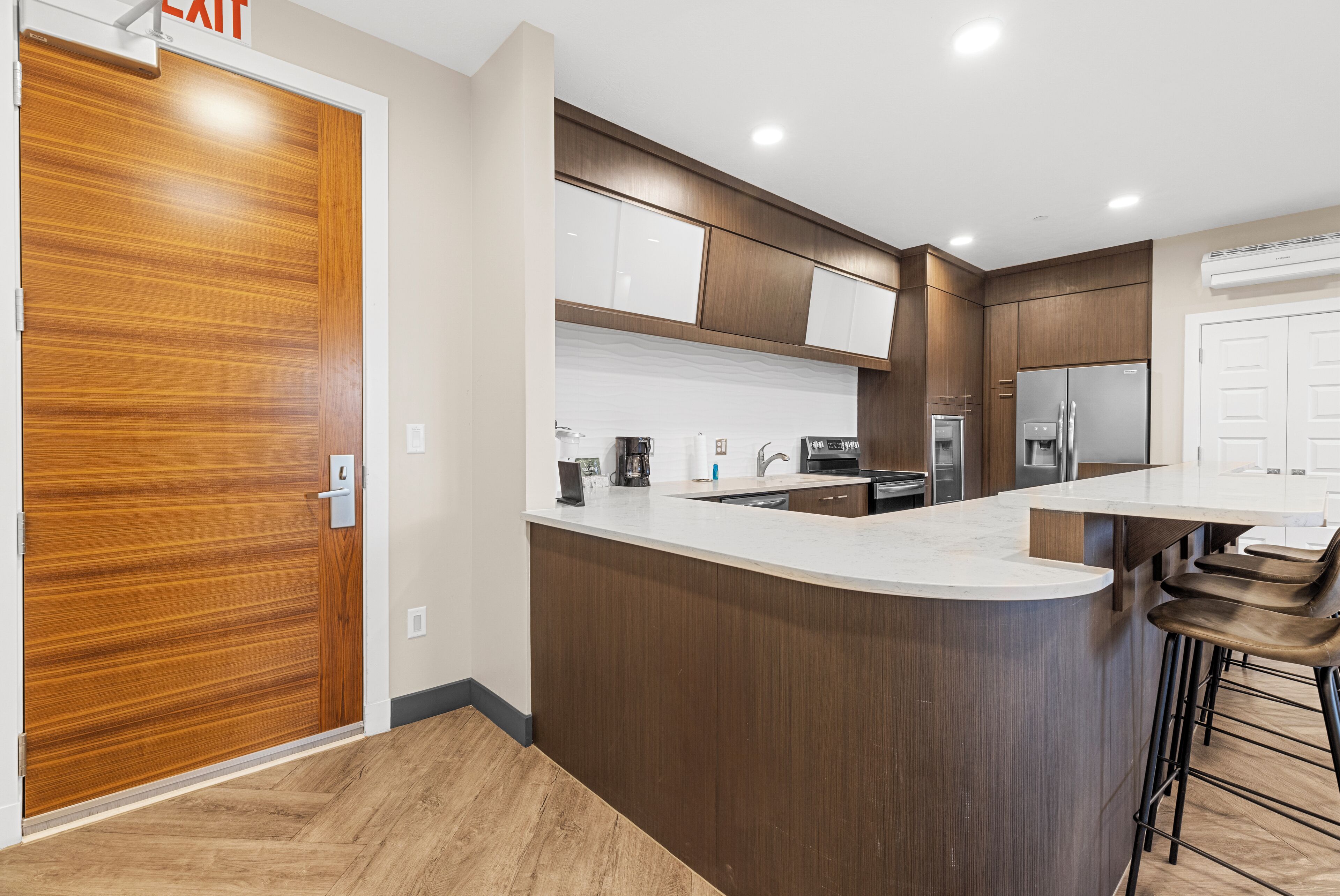 A modern kitchen with wooden cabinets, a white countertop, and a built-in island with bar stools.