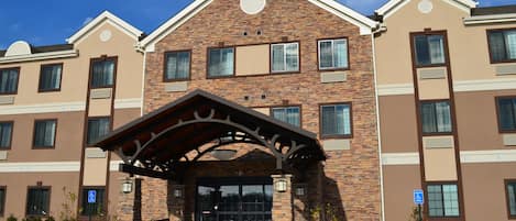 Un hôtel à plusieurs étages, doté d’une façade en briques, d’une entrée couverte et d’un parking comprenant des places réservées aux personnes handicapées.