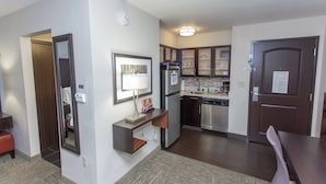 A modern kitchen with stainless steel appliances, a built-in oven, and a dishwasher. There is a small seating area with a table and chairs. - Staybridge Suites Bowling Green by IHG (Bowling Green)