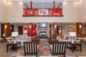 A spacious lobby with a fireplace, two sofas, and a large red sculpture. - Staybridge Suites Bowling Green by IHG (Bowling Green)