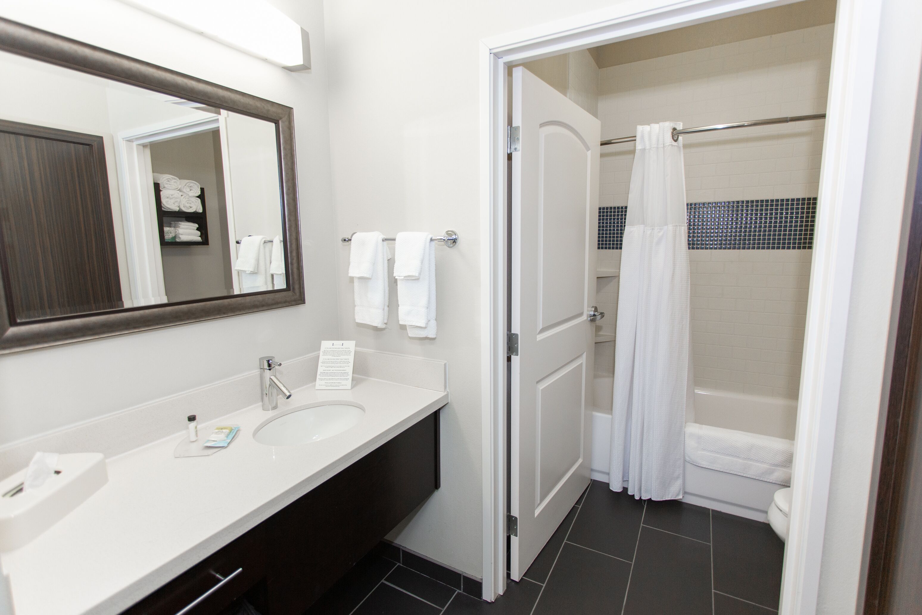 A bathroom with a white sink, a mirror, and a shower with a curtain.