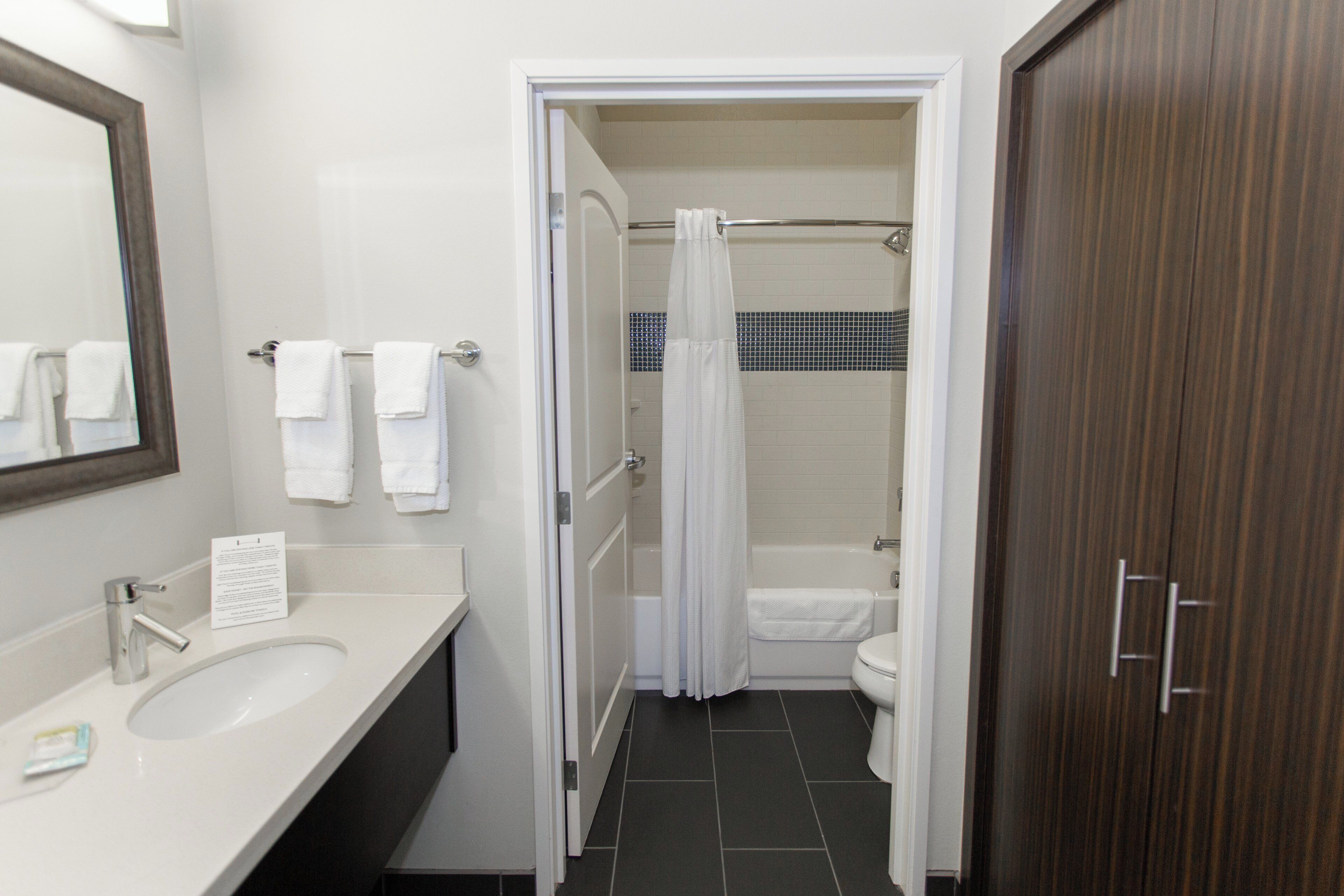 A bathroom with a sink, mirror, and a shower area with a curtain.