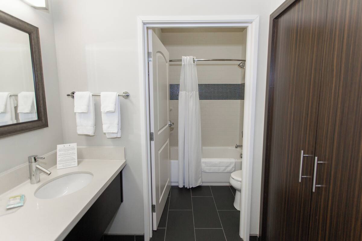Een badkamer met een wastafel, spiegel en douchecel met gordijn.