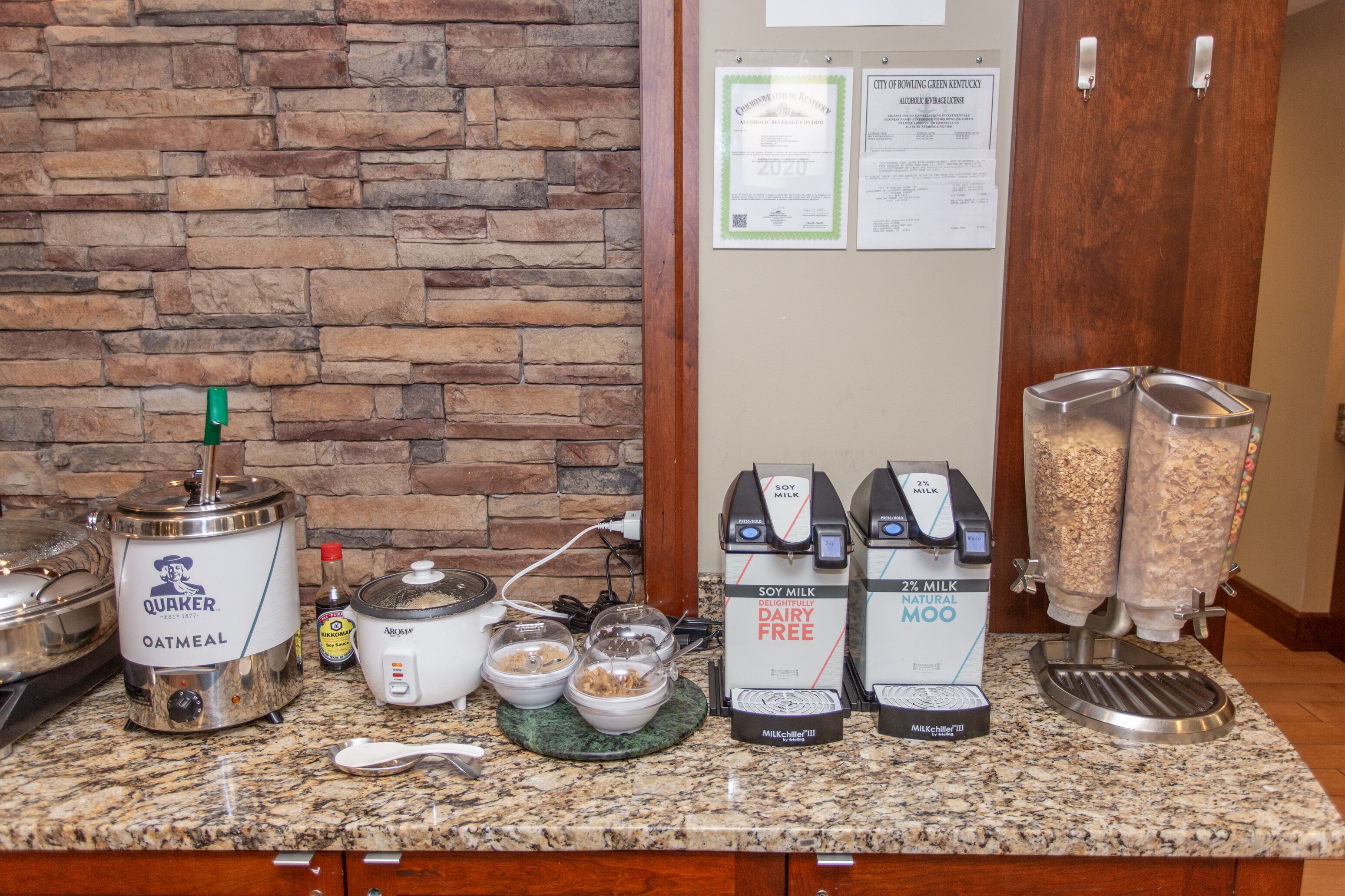 Un banco della colazione con una pentola per cuocere l'avena Quaker, erogatori di latte di soia e latte al 2%, e un frullatore.