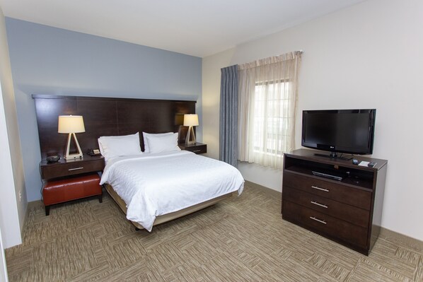A hotel room with a large bed, a TV, a nightstand with lamps, and a dresser. - Staybridge Suites Bowling Green by IHG (Bowling Green)