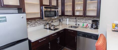 A compact kitchen with a refrigerator, microwave, stove, sink, and dishwasher.