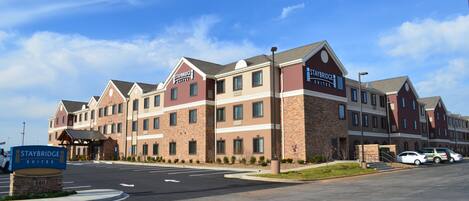 A Staybridge Suites hotel with a brick facade, multiple windows, and a clear sky.