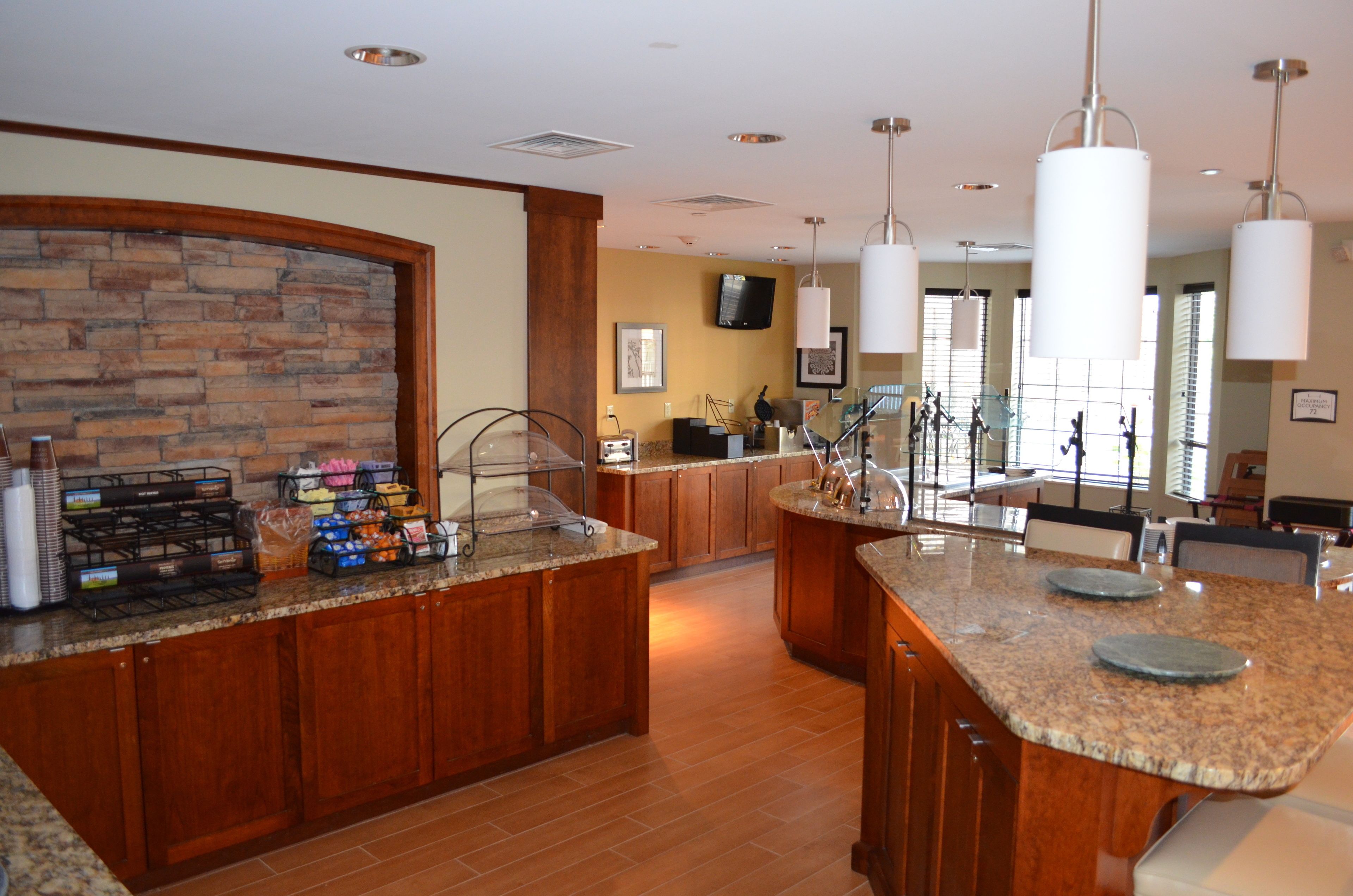 A spacious kitchen with granite countertops, wooden cabinets, and a stone backsplash.