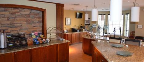 A spacious kitchen with granite countertops, wooden cabinets, and a stone backsplash.