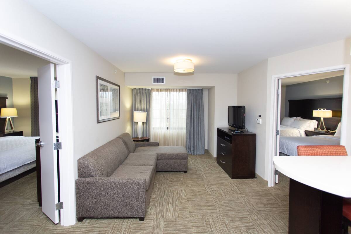 Een hotelkamer met een grote bank, een bureau, een televisie en een bed.