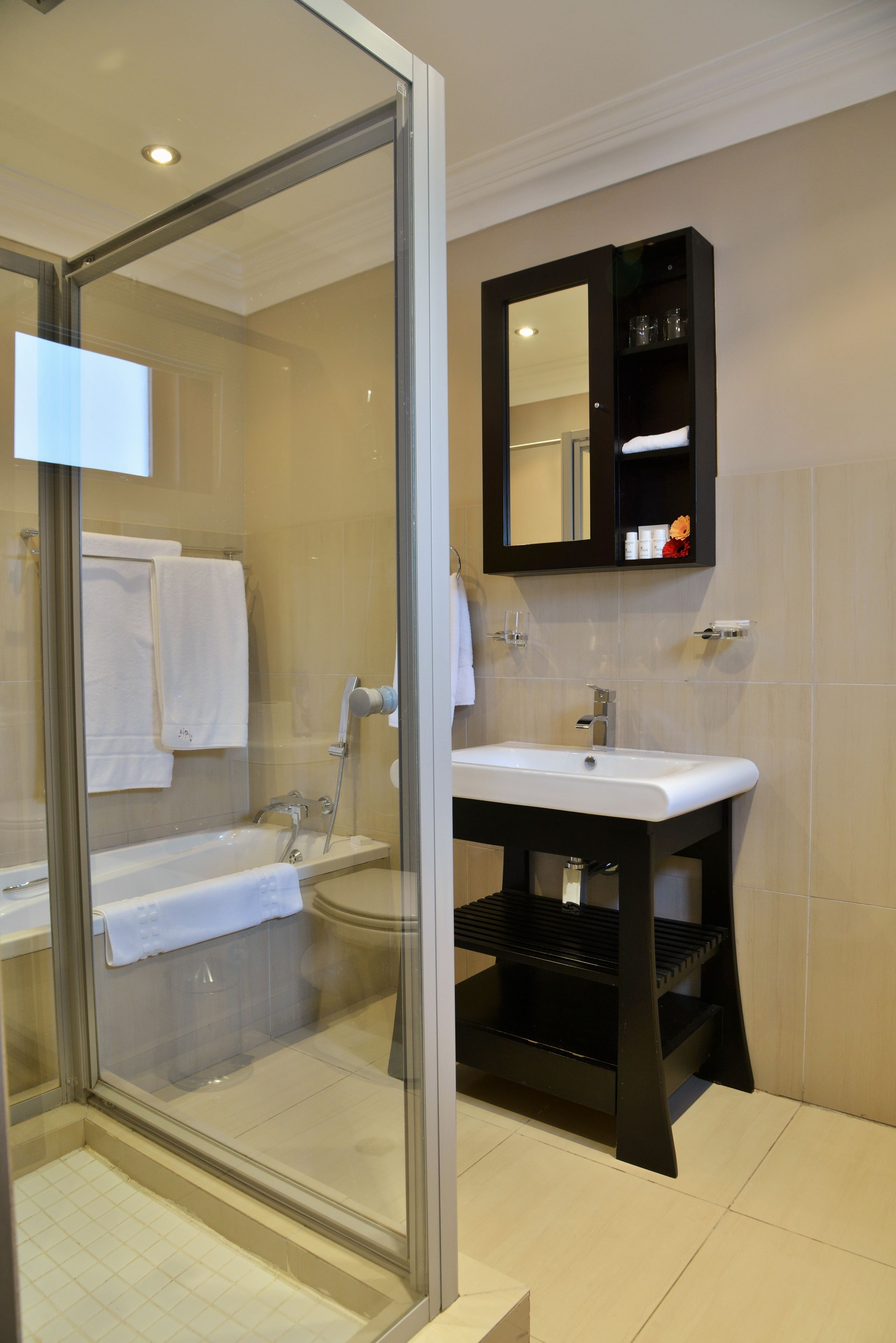 A modern bathroom with a glass-enclosed shower, a white sink, and a black vanity.
