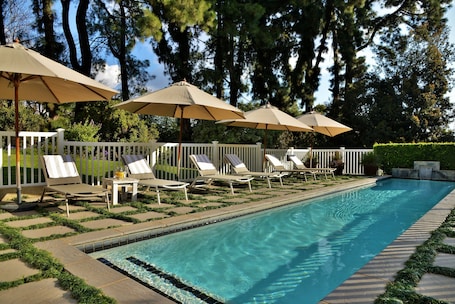 Una piscina al aire libre, sombrillas, sillones reclinables de piscina