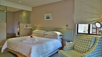 A hotel room with a large bed, a chair, a mirror, a window with a view, and a picture on the wall.