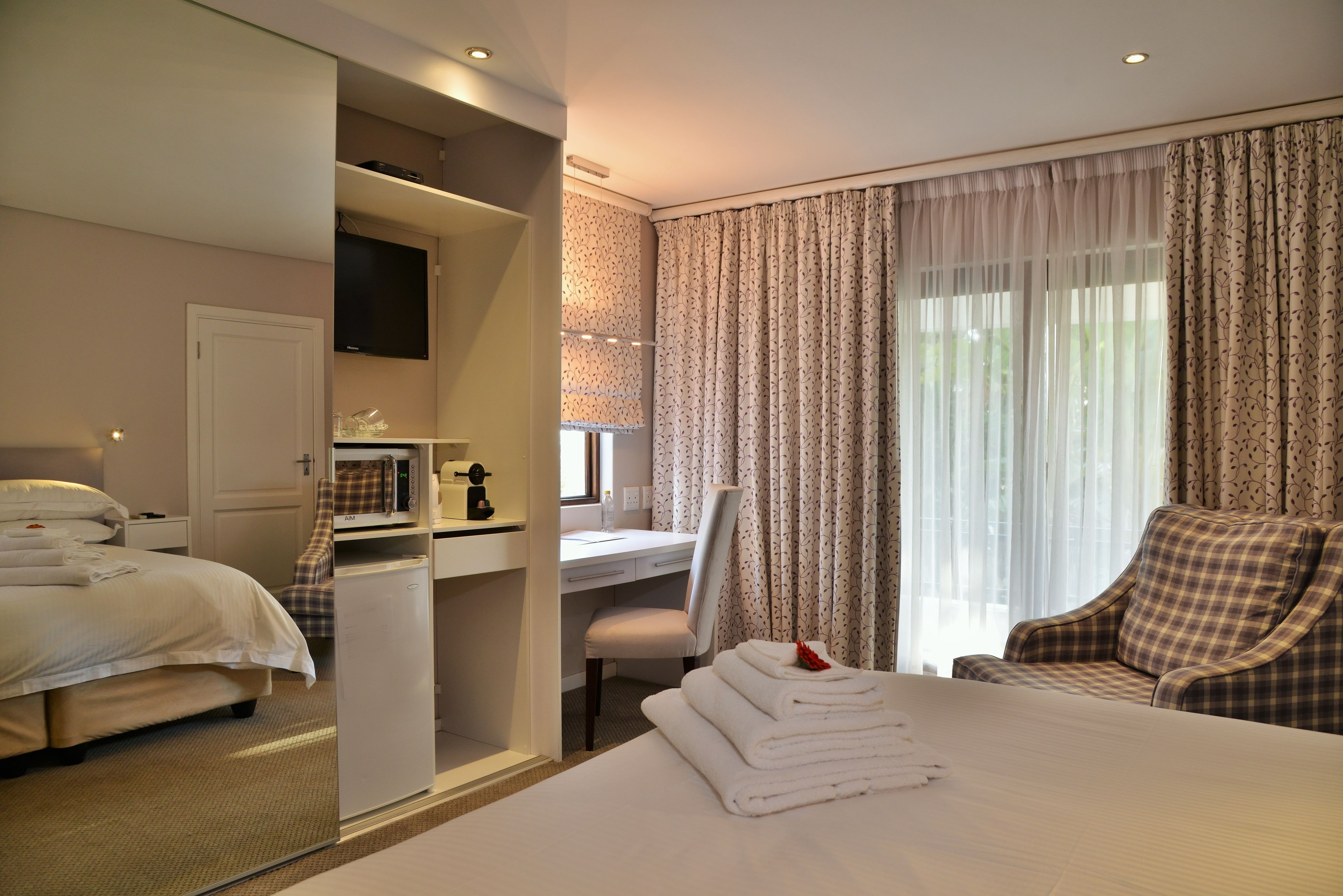 Una habitación de hotel con una cama, un escritorio, una silla y un televisor.