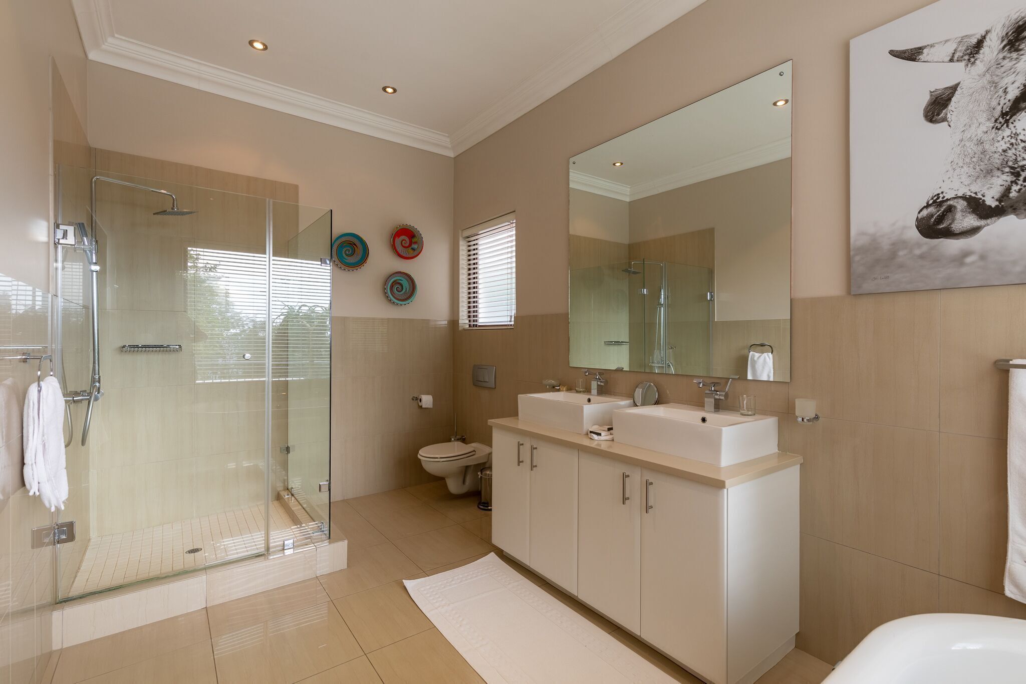 A modern bathroom with a glass-enclosed shower, a double sink vanity, and a large mirror.