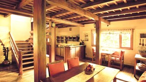 A wooden staircase leading to a kitchen area with a dining table set for four. - Windermere Estate (Devikolam)