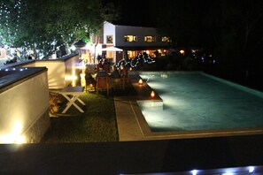 A swimming pool area with a small deck, seating, and ambient lighting.