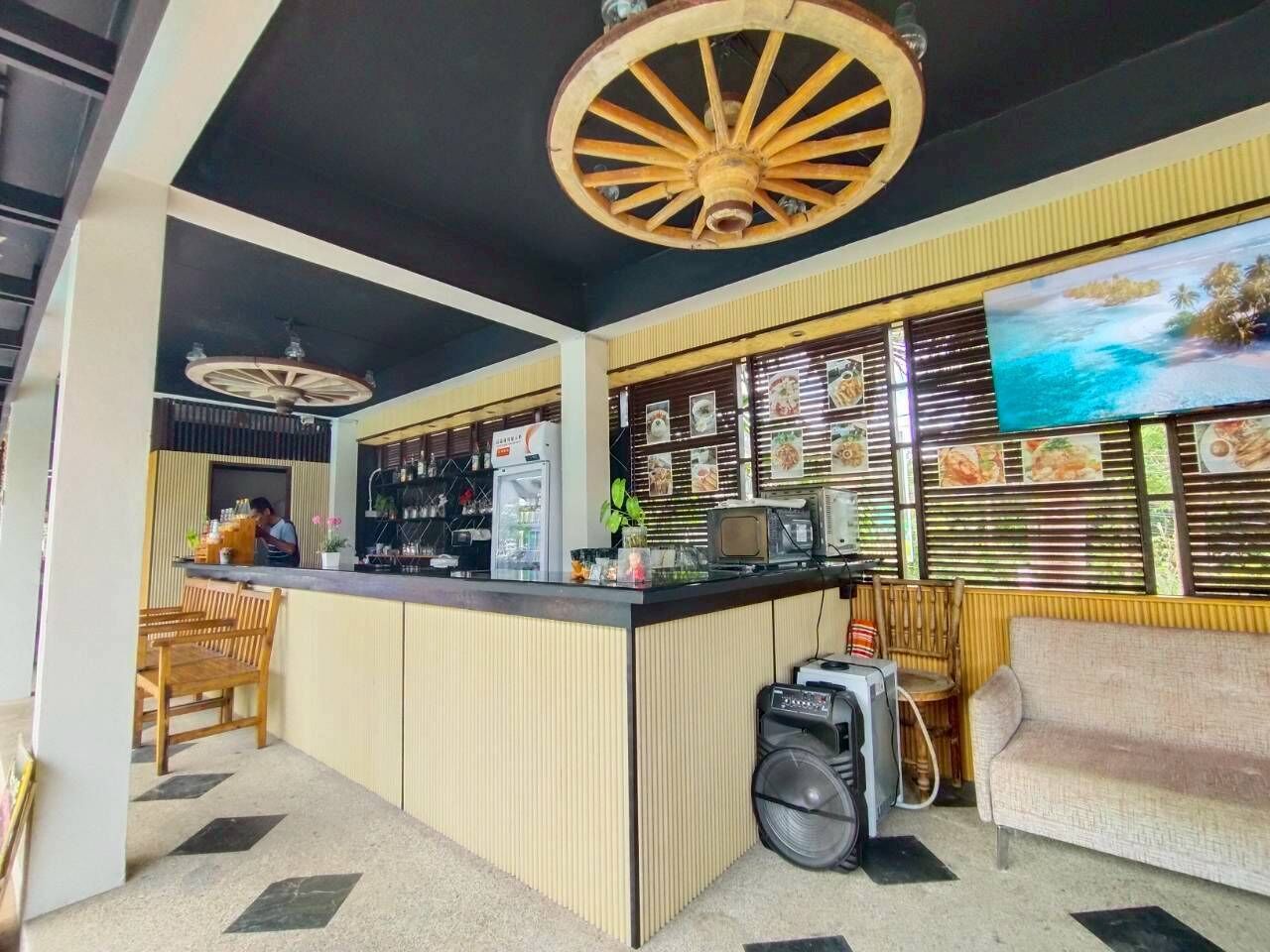 Un restaurante con mostrador, zona de mesas y una gran pared que muestra imágenes de comida.