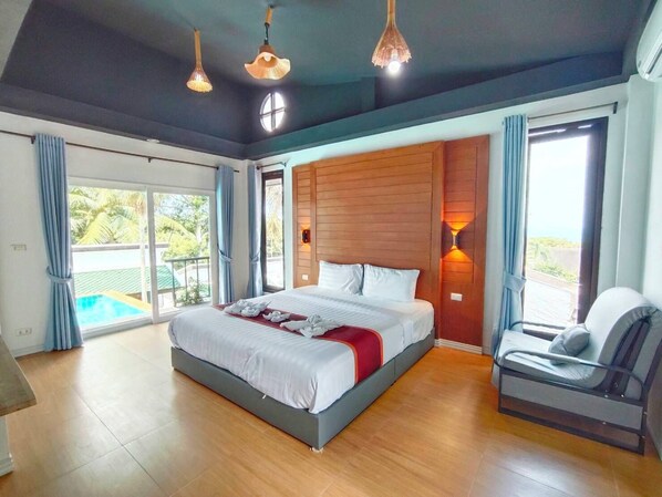 A spacious bedroom with a large bed, a chair, and a view of a swimming pool. - Sasitara Residence (Koh Samui)