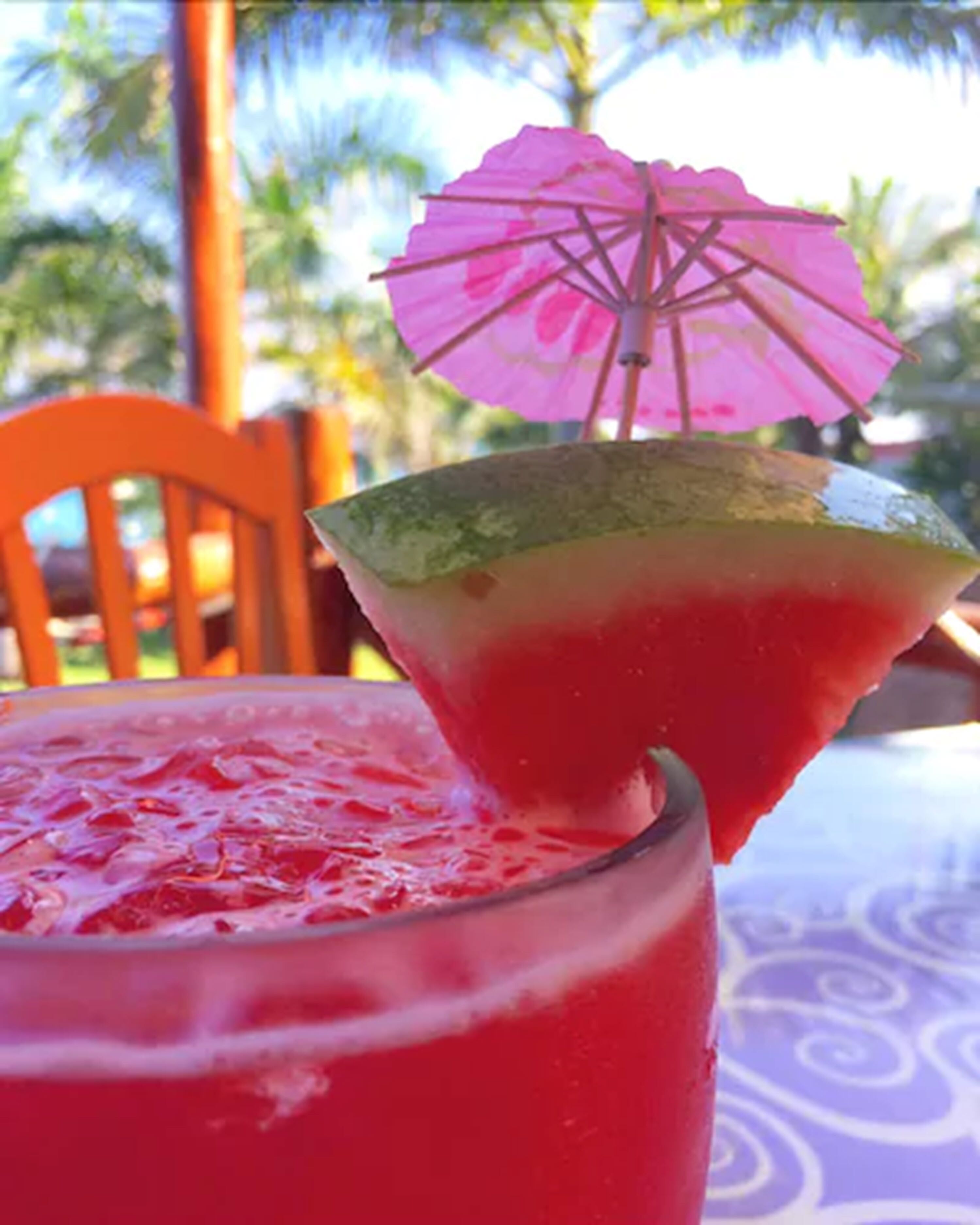 Una bebida tropical con un paraguas rosa sobre una mesa.