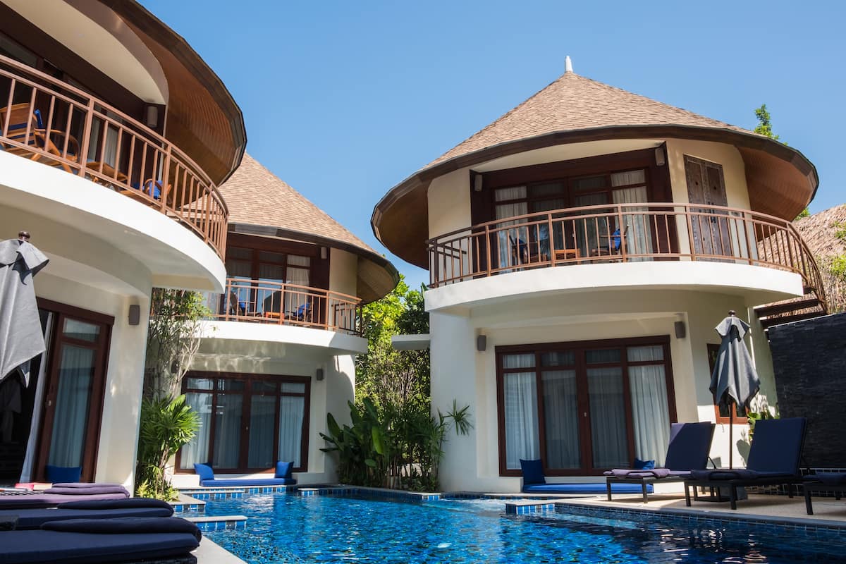 Un resort con piscina, sillas de descanso y un edificio de dos pisos con balcón.