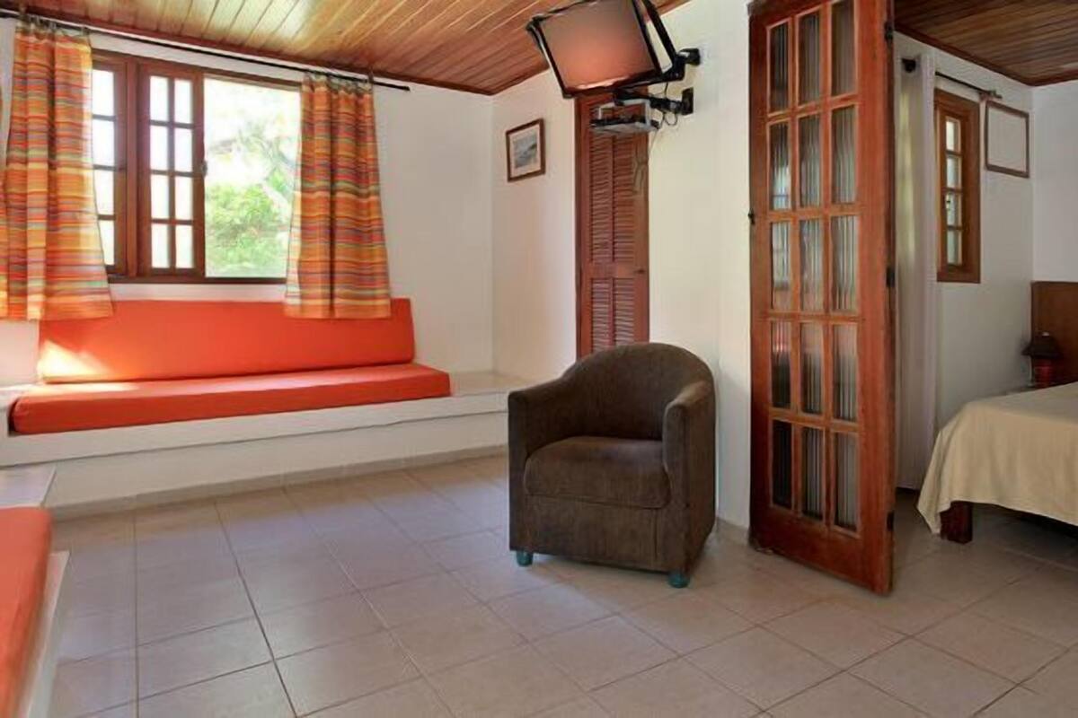 Une pièce comprenant un lit, une chaise, une fenêtre avec des rideaux et un téléviseur fixé au mur.