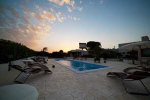 A pool area with lounge chairs and umbrellas, surrounded by greenery and a clear sky. - Le Zarafe (Caltabellotta)