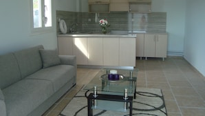 A modern kitchen with a glass coffee table, a sofa, and a kitchen island. - King's View (Lesvos)