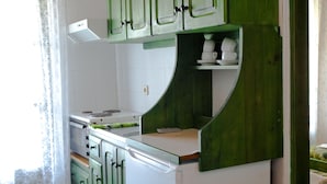 A kitchen with green cabinets, a white countertop, and a built-in oven. - Camelia Studios (Skiathos)