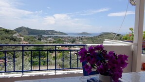 A balcony with a view of a coastal landscape, including hills and a body of water. - Camelia Studios (Skiathos)