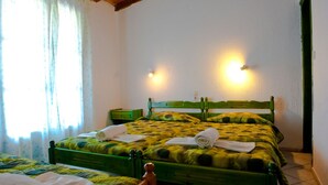 A room with a green bed, two bedside tables, and a window with curtains. - Camelia Studios (Skiathos)