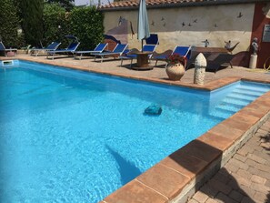 A swimming pool with clear blue water, surrounded by lounge chairs and a mural on the wall. - Locanda del Principato (Castiglione del Lago)