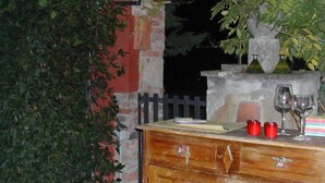 Una zona de bar con mostrador de madera, pared de piedra y una planta en maceta.