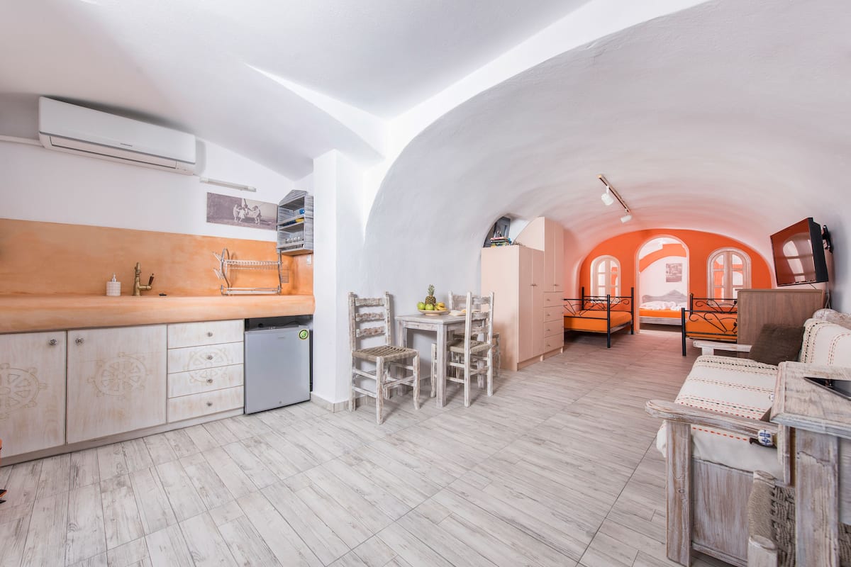 Una cocina amplia con encimera de madera, armarios blancos y un comedor con mesa y sillas.