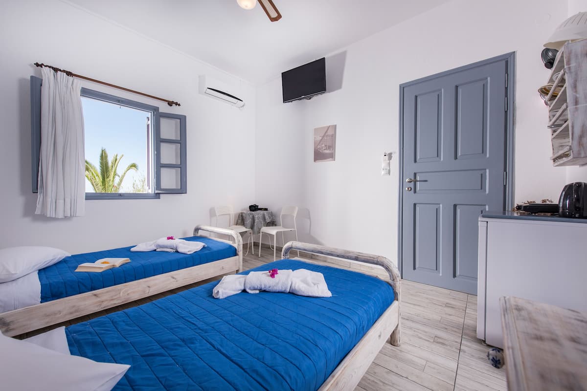 Habitación de hotel con dos camas, un escritorio, una silla, un televisor y un armario.