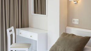 A hotel room with a bed, a desk, a chair, a pillow, a wall-mounted light, and a window with curtains. - Hostal Residencia Sutimar (Calvia)