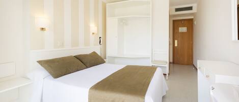Una habitación de hotel con cama, mesitas de noche, armario, silla y baño con bañera.