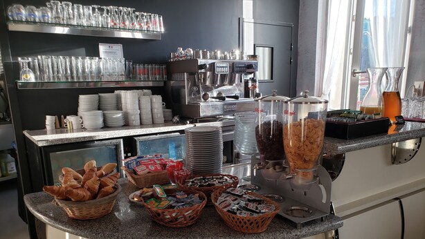 A breakfast buffet with croissants, pastries, and coffee machines. - Hotel Du Touring (Saint-Cere)