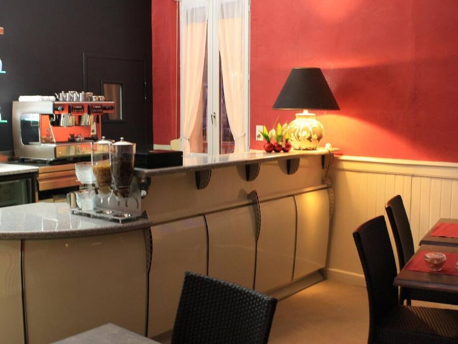 A compact kitchen with a counter, a coffee machine, and a table with chairs.