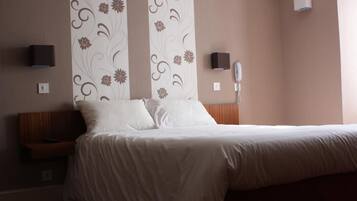 Une chambre d’hôtel comprenant un lit, une table de chevet, un téléphone fixé au mur et un panneau décoratif mural.