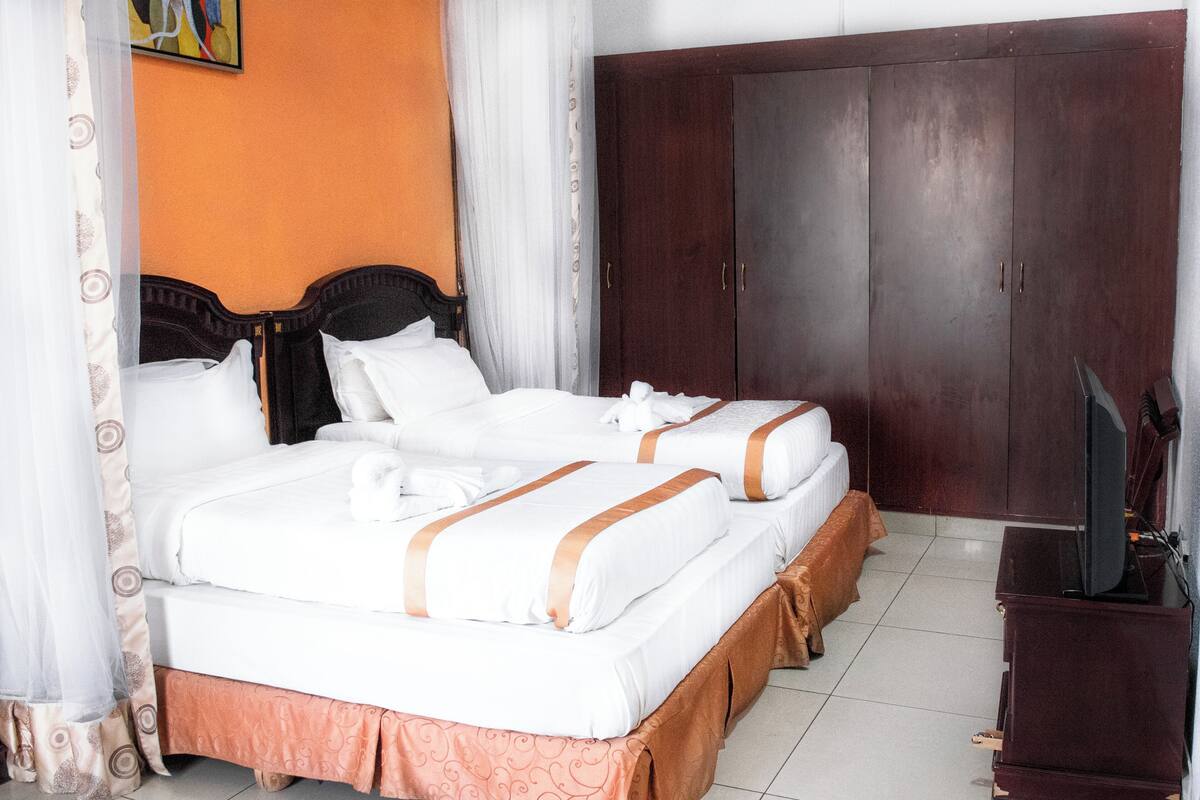Una habitación de hotel con cama doble, un armario y televisión.