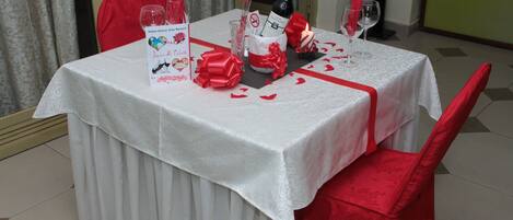 A table set for two with a white tablecloth, red napkins, and a bottle of wine.
