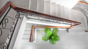 A staircase with a wooden handrail, metal balusters, and a white wall with a decorative metal railing. - Hotel Dolce Vita Resort (Bujumbura)