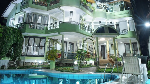 A multi-story hotel with a swimming pool, balconies with plants, and a well-lit exterior. - Hotel Dolce Vita Resort (Bujumbura)