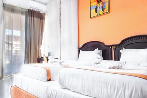 Habitación de hotel con dos camas, un ventanal con cortinas, un cuadro en la pared y vistas al exterior.
